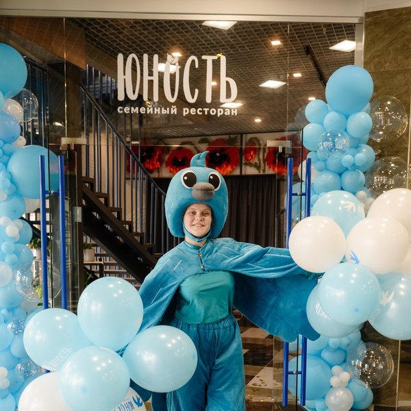 Маскот ресторана Юность позирует на фоне входной группы ресторана